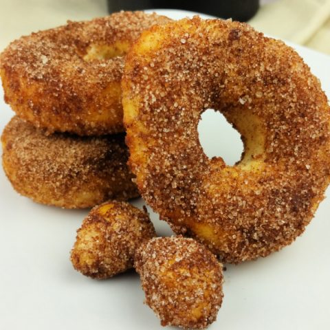 Cinnamon sugar air fryer donuts on while plate with black coffee mug in background