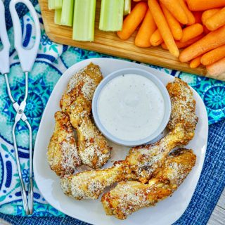 Garlic Parmesan Air Fryer Wings on white plate with fresh cut veggies in background